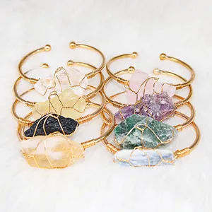 Detail view of handmade wire-wrapped gold-plated cuff bracelets with various raw crystals