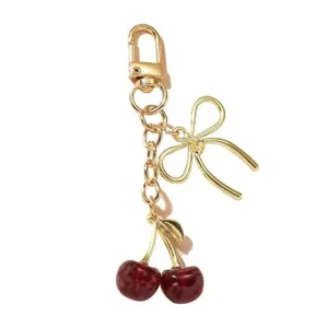 Détail du porte-clés cerise avec nœud doré et pendentifs en forme de fruits rouge foncé