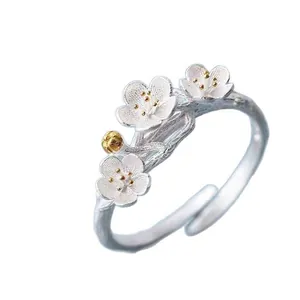 Macro view of a silver plum blossom open ring with gold stamen accents