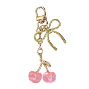 Vue détaillée d'un porte-clés cerise en résine rose avec nœud doré et fermoir