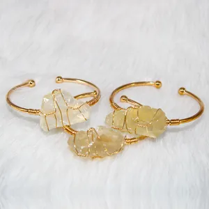 Detail view of handmade gold wire wrapped natural raw yellow crystal cuffs on white fur