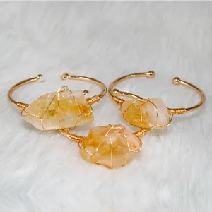 Close-up of three wire-wrapped bracelets with irregular raw yellow crystals on white fur.