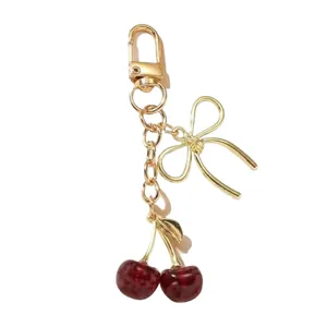 Élégant porte-clés cerise doré avec un nœud et des pendentifs de fruits rouge foncé réalistes