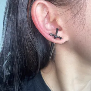 Close-up detail of a black sword-shaped dagger earring worn on an Asian model's ear