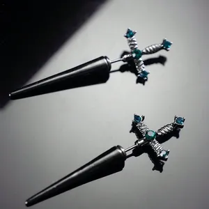Detailed macro shot of gothic sword shaped stud earrings with emerald green rhinestones