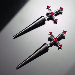 Detailed macro view of gothic sword stud earrings with faceted red gemstones in dark metal