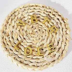Close-up of 18k gold plated stainless steel chubby bubble letter pendants on mat