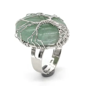Detail view of an oval green crystal ring wrapped in silver tree of life wire pattern.