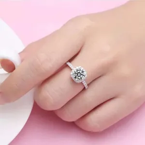 Primer plano de un anillo de halo de plata brillante con pavé de diamantes en un dedo
