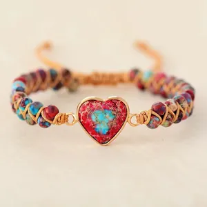Gros plan d'un bracelet tissé main avec une pierre impériale rouge en forme de cœur.