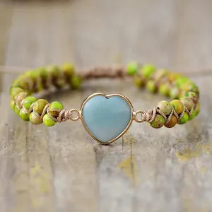 Détail d'un bracelet en pierre impériale tressé à la main en forme de cœur sur bois