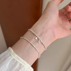 Makro-Detail von minimalistischen Silberarmbändern mit Seestern- und Muschelanhängern