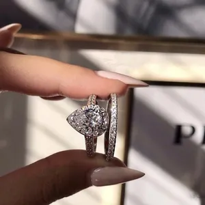 Close-up detail of a sparkling pear-shaped halo engagement ring set with eternity band