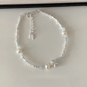 Detailaufnahme eines silbernen Seestern-Armbands mit Perlen und hellblauen Perlen