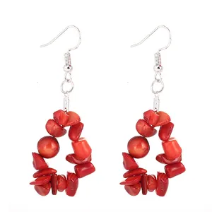 Gros plan de boucles d'oreilles pendantes en éclats de pierre naturelle rouge vif