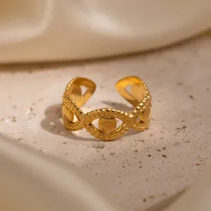 Close-up of a gold-plated evil eye ring on a textured stone surface with silk.