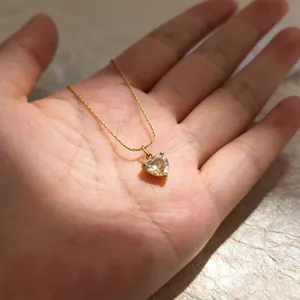 Detailopname van een gouden halsketting met een glanzende hartvormige hanger