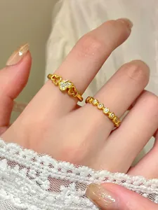 Dettaglio di eleganti anelli dorati con cuore e perline decorati con pietre brillanti.