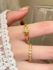 Dettaglio ravvicinato di eleganti anelli d'oro a cuore traforato e pavé di diamanti al dito