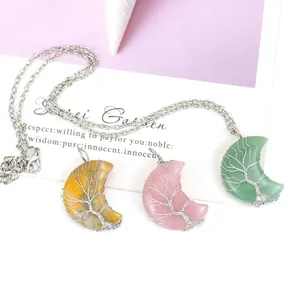Gros plan de trois pendentifs lune en pierre naturelle avec motif arbre de vie en fil