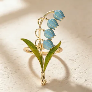 Dettaglio dell'anello portatovagliolo a mughetto di lusso con fiori in smalto blu e foglie verdi