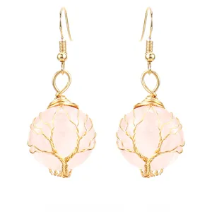 Dettaglio dell'albero della vita in filo d'oro su orecchini tondi in cristallo rosa
