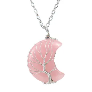 Gros plan d'un pendentif lune en quartz rose fait main avec motif arbre de vie filé.