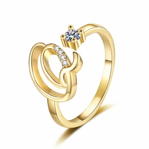 Macro view of gold-tone ring with zircon-encrusted letter design and solitaire stone.