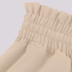 Close-up view of the high-waisted elastic paper bag waistband on beige wide-leg trousers.