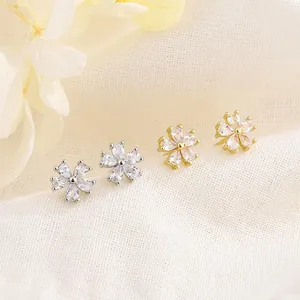 Primer plano de pendientes de flores de cerezo con circonitas en tonos plata y oro