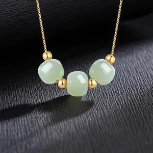 Detail van een natuurlijke Hetian jade ketting met gouden kralen op zwarte grond