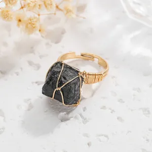 Close-up detail of wire-wrapped raw black tourmaline stone on a gold adjustable ring band