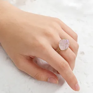 Close-up of handmade gold wire wrapped rose quartz irregular raw stone ring on hand.