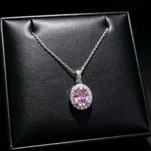 Macro detail of elegant oval pink gemstone pendant with sparkling halo on silver chain.