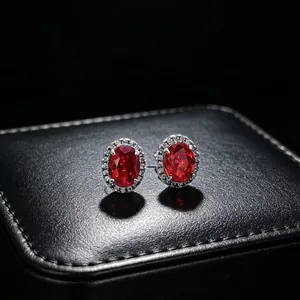 Macro view of elegant oval red gemstone stud earrings featuring a moissanite halo