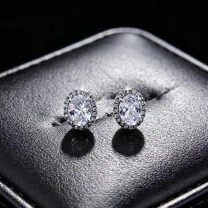 Close-up of sparkling oval moissanite halo stud earrings on black leather display box