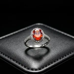 Close-up of a stunning oval red gem ring set on a black textured jewelry display cushion