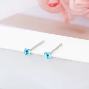 Vue macro détaillée de petits clous d'oreilles en forme de cœur bleu clair en argent sterling
