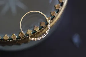 Primo piano di un anello minimalista placcato oro 14K con zirconi su un supporto vintage
