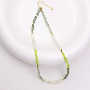 Close-up of handmade natural pearl necklace with green stones and gold accents.