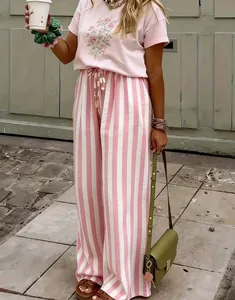 Modell trägt lässige rosa-weiß vertikal gestreifte weite Hosen für einen Sommer-Street-Look