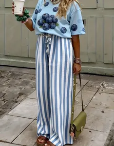 Styling-Detail einer blau-weiß gestreiften Hose mit einem T-Shirt mit Heidelbeergrafik