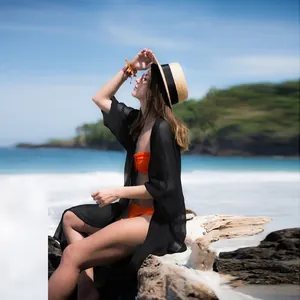 Detail view of a black chiffon crinkle beach cover-up worn over an orange bikini