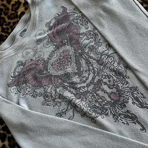 Detalle de estampado de alas vintage en camiseta de manga larga gris de punto gofrado
