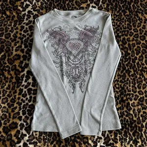 Primer plano del estampado gráfico vintage de alas y corazón en camiseta gris de punto gofre