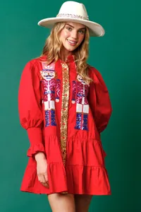 Close-up of a red Christmas dress featuring sequin nutcracker embroidery and long sleeves