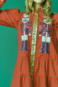 Detailed close-up of festive red Christmas dress featuring sequined nutcracker motifs
