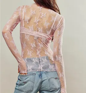 Close-up detail of the intricate floral lace texture on a sheer pink long-sleeve top