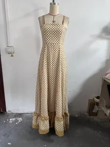 Full view of a brown gingham camisole maxi dress with a ruffled hem on a mannequin.