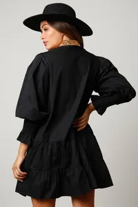 Back view of black puff sleeve mini dress with ruffled hem and chic wide-brim hat